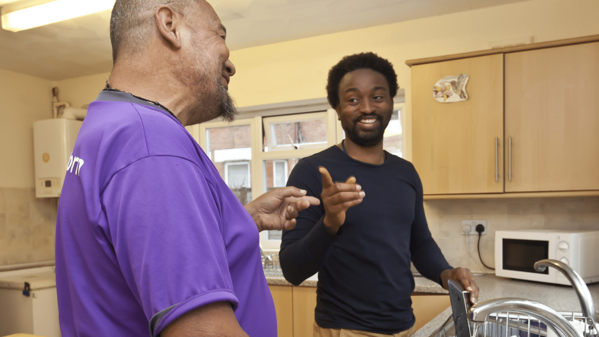 Two Pivotal Homes team members talking in a supported living property kitchen