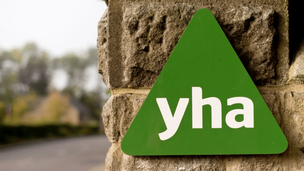 YHA sign displayed on a stone wall outside a hostel location